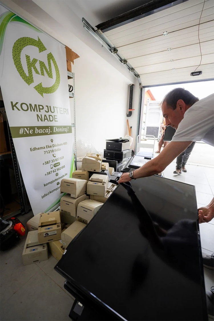 Prijem donirane opreme u Kompjuterima nade, uz osobu koja prenosi veliki monitor.